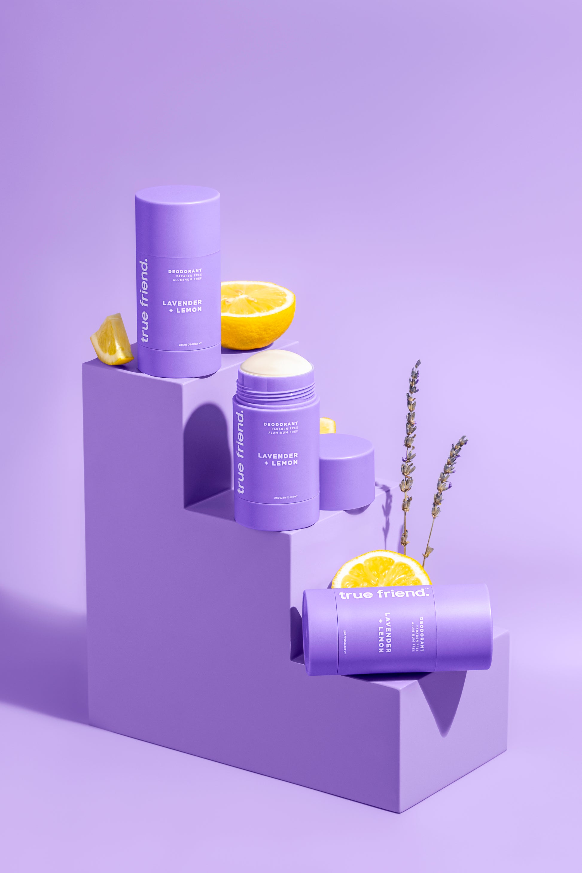 Three lavender + lemon True Friend deodorants on a step with lemons and lavender