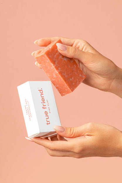 hands holding a pink clay True Friend soap bar with the True Friend soap bar box
