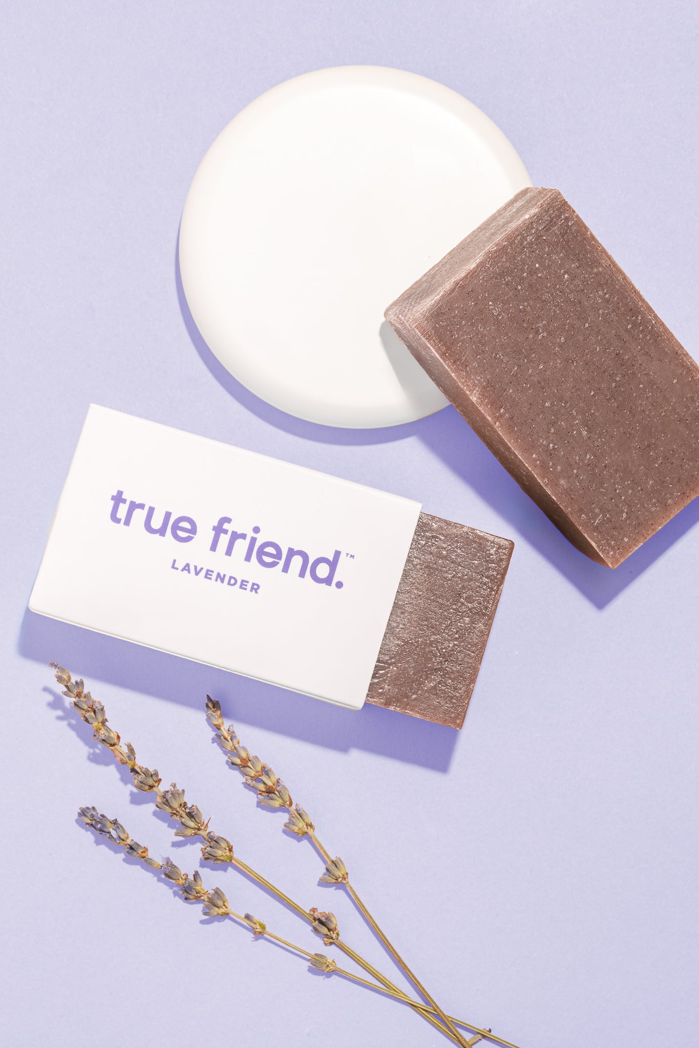 A bar of soap next to its packaging, with a small white box labeled 'TRUE FRIEND. Lavenders.
