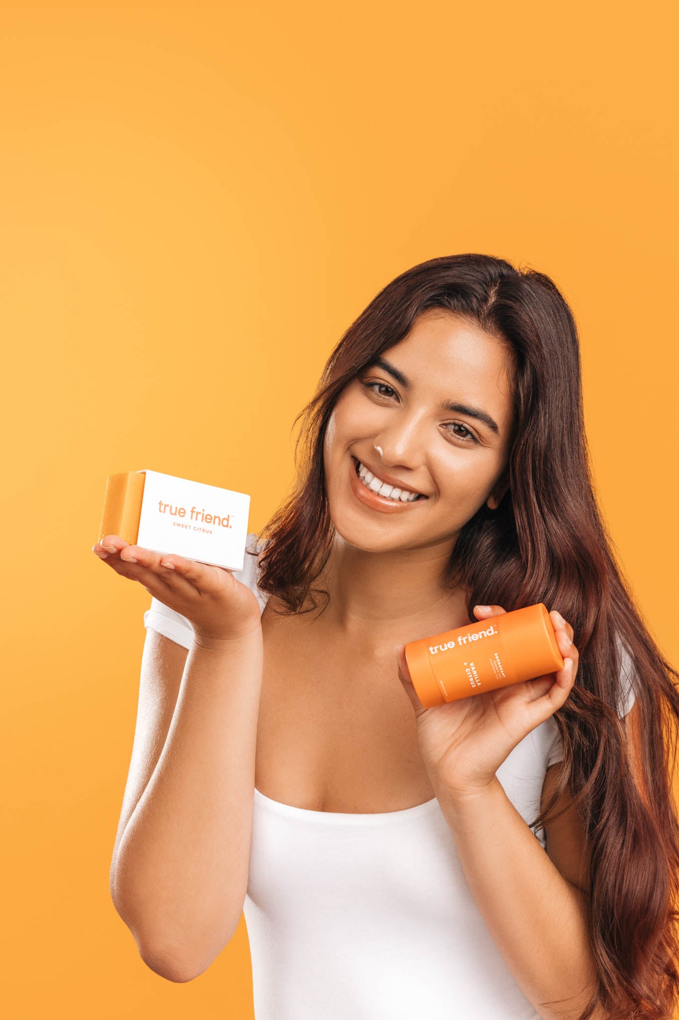 woman holding a True Friend organic citrus soap bar and nontoxic vanilla + citrus deodorant